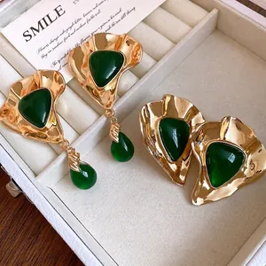 Vintage style gold earrings featuring green resin triangles displayed in a jewelry box