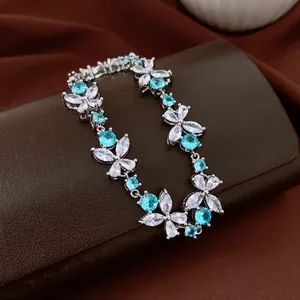 Elegant flower bracelet featuring blue and clear cubic zirconia on a brown leather surface