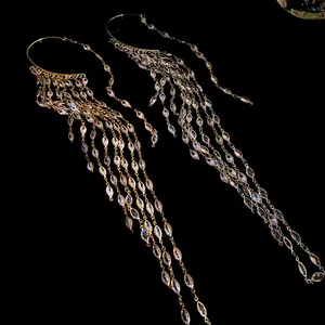 Close-up of elegant zircon tassel ear cuffs in gold and silver on black background