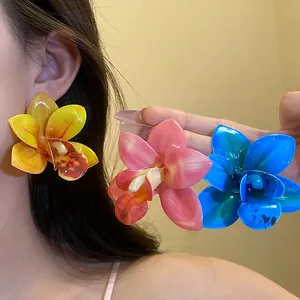 Dettaglio di grandi orecchini a lobo a forma di orchidea in vari colori vivaci