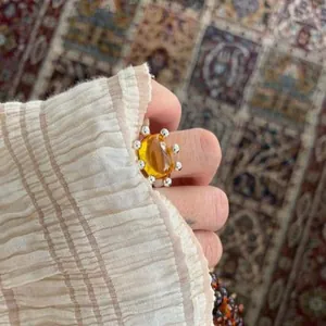 Detailed close-up showing a round yellow resin ring with silver bead trim on a finger.