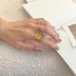 Elegant close-up shot of yellow resin open ring with stud details worn on woman's hand