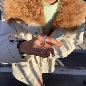 Detailed view of 18k gold plated amber resin open rings worn on a hand outdoors