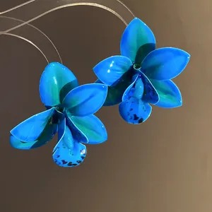 Primo piano di orecchini a fiore di orchidea blu brillante con finitura in resina