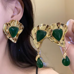 Close-up of vintage emerald green triangle earrings with gold-tone hammered metal