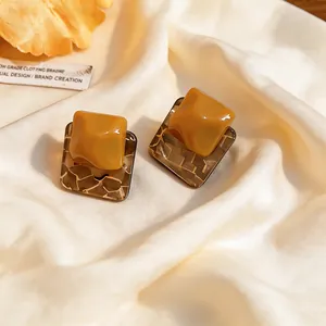 Handcrafted unique square resin earrings with yellow textured design on cream silk fabric