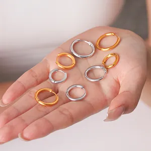 Close-up of assorted gold and silver stainless steel hoop earrings held in hand