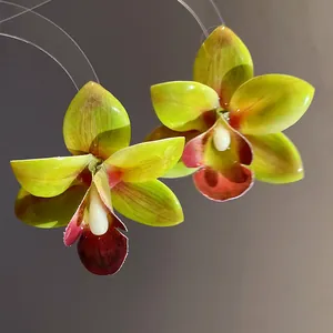 Primo piano di orecchini a forma di orchidea verde lime con finitura in resina
