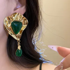 Macro detail of vintage emerald green resin earrings with elegant gold metal texture