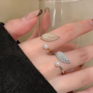 Detail view of delicate gold and silver wing-shaped open rings with pearls and zircons