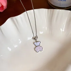 Detailansicht eines perlmuttartigen Glasbären-Anhängers an einer feinen silbernen Kette