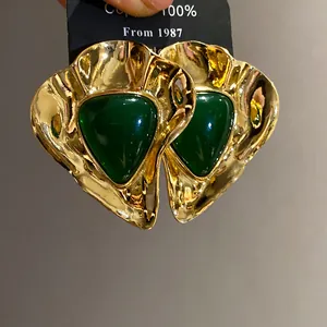 Detail shot of vintage gold earrings featuring a dark green resin triangular center