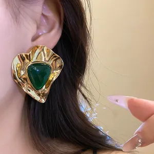 Close-up detail of a vintage gold earring with a green triangle resin stone