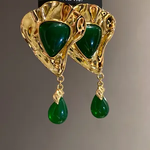 Close-up of vintage style gold-tone earrings with green resin and teardrop drops.