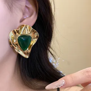 Close-up detail of a vintage gold-toned hammered earring with a green resin triangle inlay.