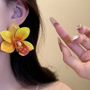 Primo piano di orecchini a forma di orchidea gialla con finitura in resina per vacanze