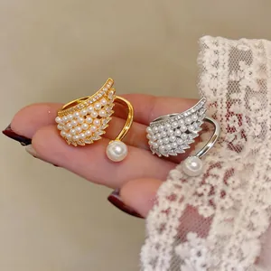 Close-up of golden and silver angel wing rings with pearls and sparkling zircons.