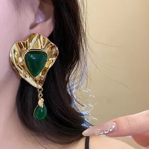 Detailed close-up showing vintage palace style gold earring with green resin on model's ear