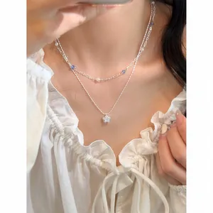 Detailed view of a double-layered necklace featuring a zircon star pendant on a model