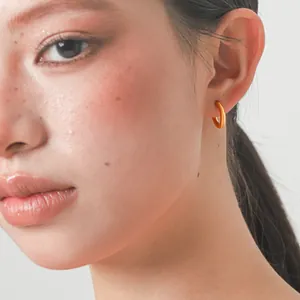Close-up detail of a minimalist gold hoop earring worn by a model for a chic look