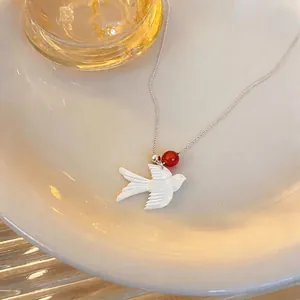 Elegant white shell swallow bird pendant necklace with a red bead on silver chain