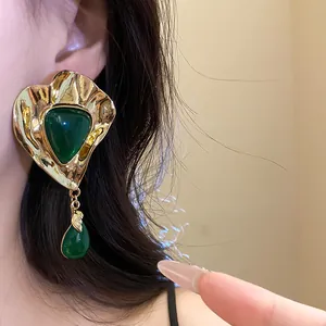 Detailed view of vintage gold triangle earrings with green resin drops on model