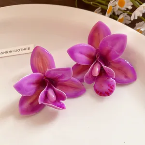 Vista macro di orecchini a fiore di orchidea viola con finitura in resina lucida