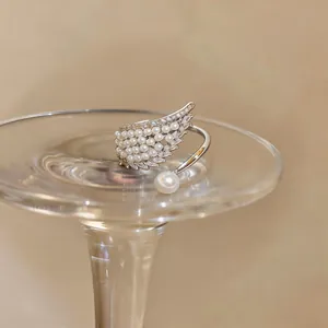 Detailed macro view of an elegant angel wing open ring with pearls and shiny zircons