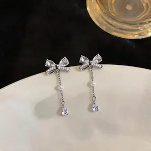 Korean style silver bow stud earrings featuring zircon accents and delicate pearl drops