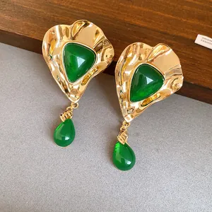 Close-up detail of vintage style gold-tone earrings featuring emerald green resin stones