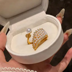 Close-up of elegant gold wing ring with embedded pearls and sparkling zircons