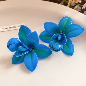 Primo piano di orecchini a lobo a forma di orchidea blu vibrante con finitura in resina.