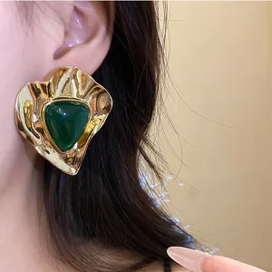 Close-up detail of vintage style gold-toned earrings with green resin triangular inlay.