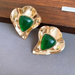 Macro view of vintage gold-tone earrings featuring triangular green resin details.