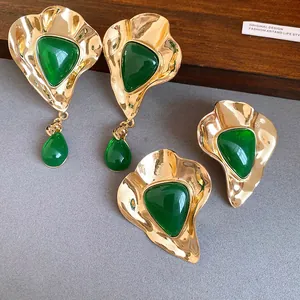 Detail of vintage palace-style earrings featuring green resin and hammered gold metal