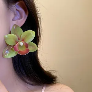 Dettaglio ravvicinato di un orecchino a fiore in resina verde e rosa su una modella