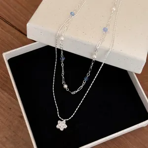 Double-layered necklace with zircon star pendant, pearls and blue beads in jewelry box.