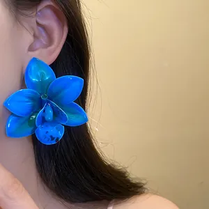 Vista dettagliata dell'orecchino a forma di orchidea blu vibrante indossato dalla modella