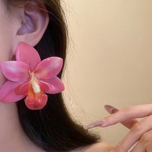 Dettaglio di un grande orecchino a fiore di orchidea rosa con finitura in resina su un modello
