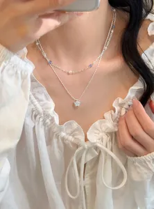 Detailed view of a silver layered necklace with a sparkling zircon star pendant on model