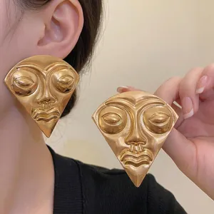 Oversized gold-toned fan-shaped face earrings with surrealist vintage mask design