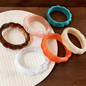 Set di braccialetti geometrici vintage in acrilico colorato su un piatto bianco testurizzato