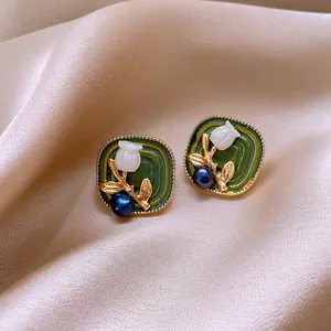 Close-up of vintage green enamel earrings with lily of the valley and blue pearl