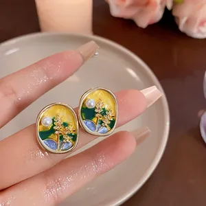 Macro detail of Monet Garden style enamel stud earrings with pearl and floral gold accents