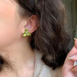 Nahaufnahme eines eleganten grünen Emaille-Blumensteckers, der von einem Modell getragen wird