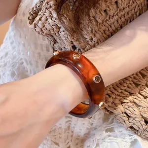 Vue détaillée d'un élégant bracelet jonc en résine ambrée avec des rivets dorés