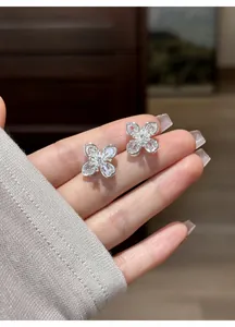 Close-up detail of exquisite clear zircon flower stud earrings held in hand for scale