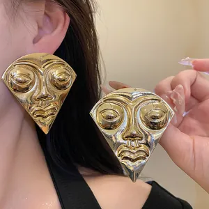 Close-up of oversized golden face portrait earrings on model for vintage aesthetic