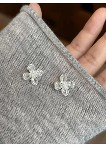 Close-up of elegant floral silver stud earrings with clear zircon stones on grey fabric
