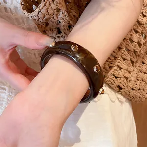 Gros plan d'un bracelet jonc en résine écaille de tortue avec des clous en ambre